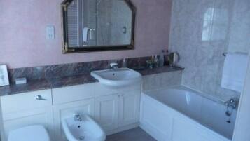 A bathroom with a toilet, bidet, sink, and bathtub.