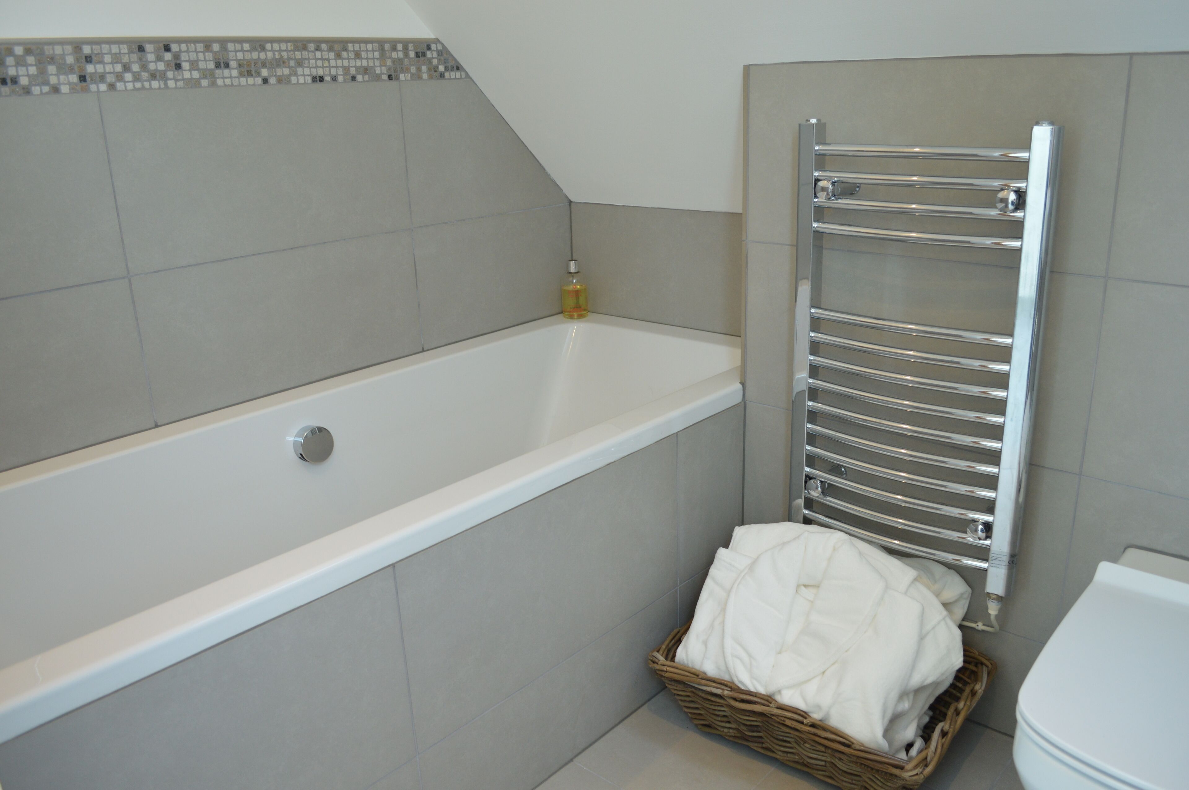 A bathroom with a bathtub, a towel rack, and a wicker basket with towels.