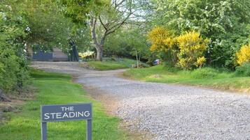A gravel path leading to a building with a sign reading 'THE STEADING.'