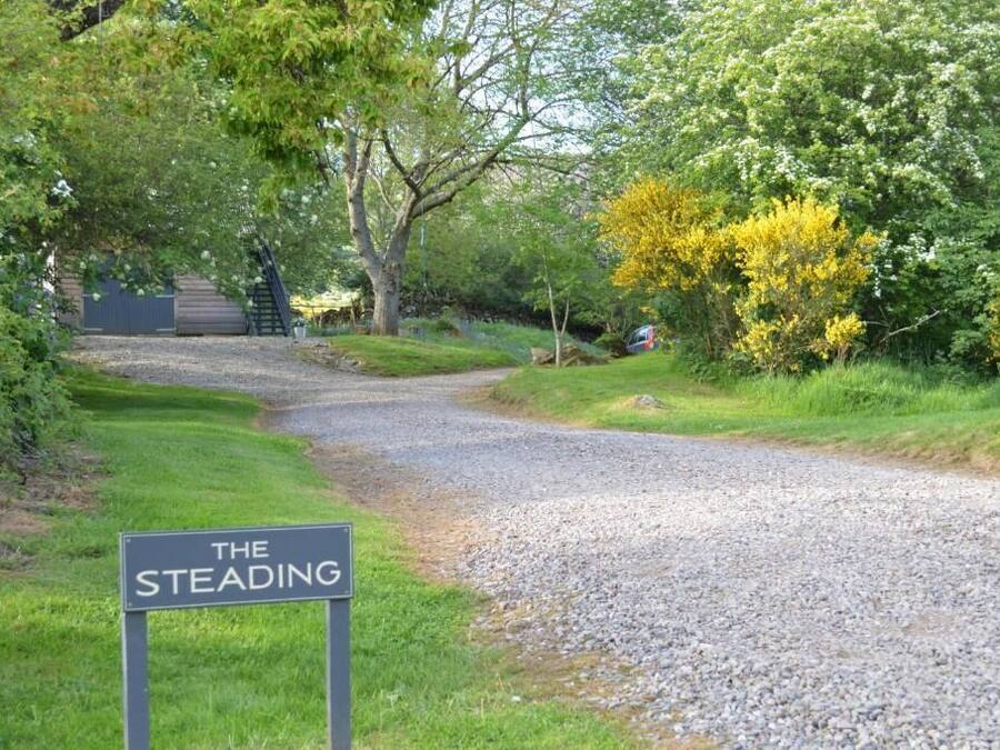 A gravel path leading to a building with a sign reading 'THE STEADING.'