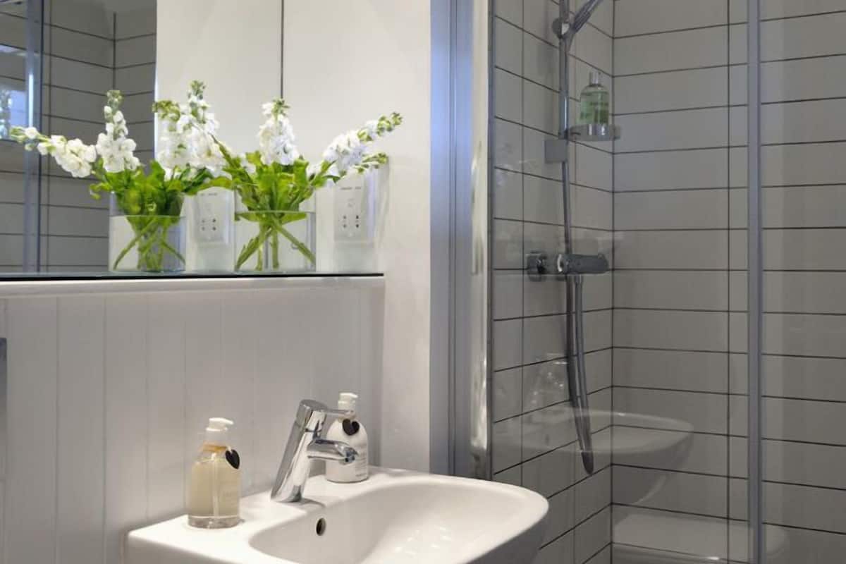 A modern bathroom with a glass-enclosed shower, a white sink, and a mirror above it.