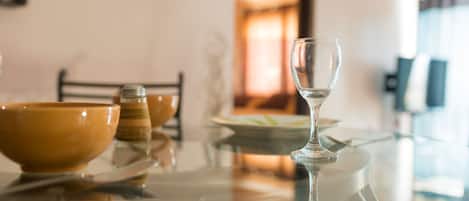 A dining table with a glass wine glass, a bowl, and salt and pepper shakers.