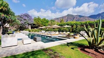 Una piscina al aire libre, sombrillas, sillones reclinables de piscina