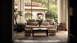 A cozy living room with a sofa, coffee table, and potted plants. - Hotel Amomoxtli (Tepoztlán)