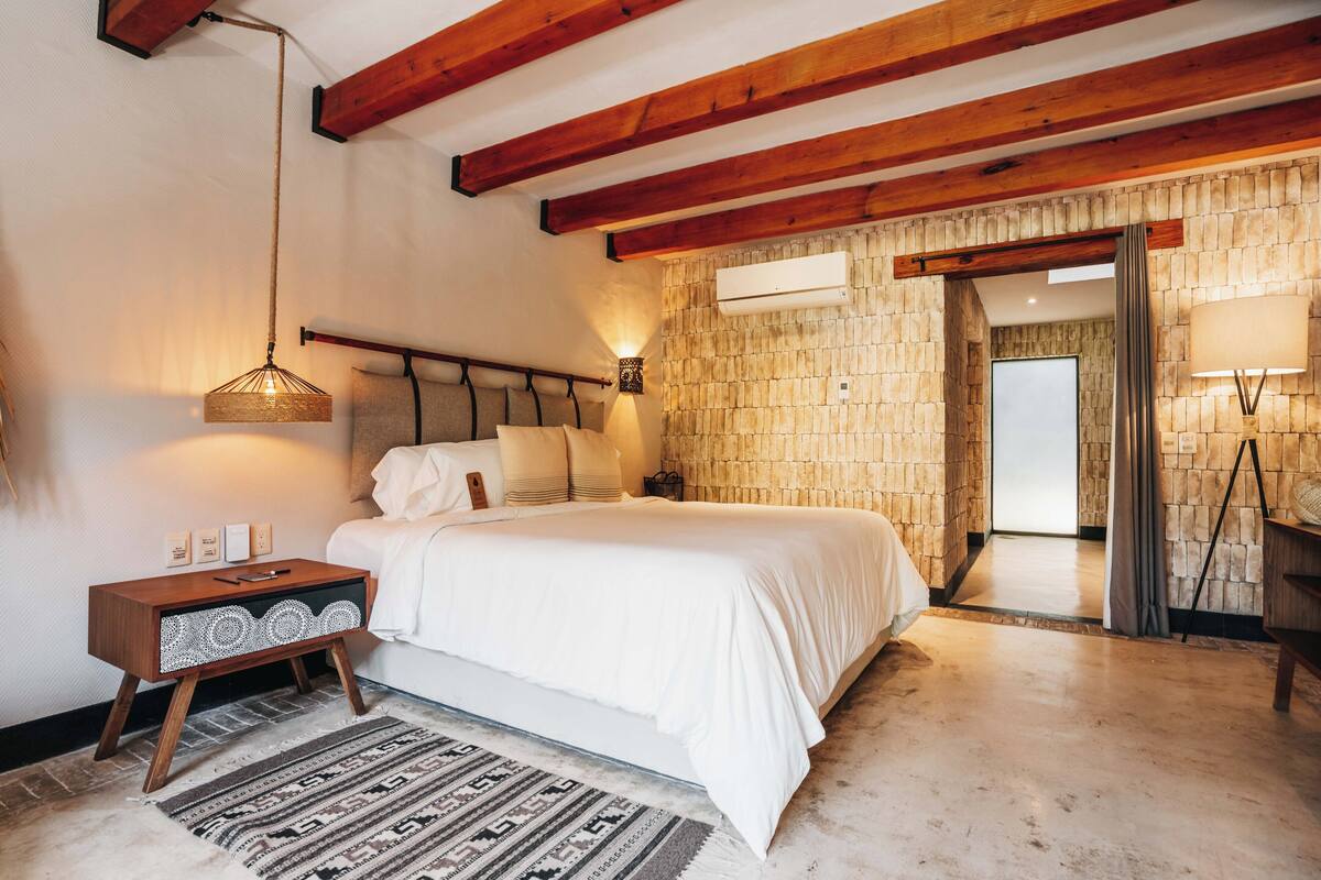 Une chambre à coucher avec un lit, une table de chevet, une lampe et un mur en pierre.