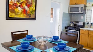 Uma sala de jantar com uma mesa de madeira posta para quatro pessoas, louças azuis e um candelabro.