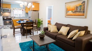 Uma sala de estar moderna com um sofá marrom, uma mesa de centro e uma área de jantar com cadeiras e mesa de madeira.