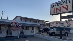 An Economy Inn with a sign listing amenities like free Wi-Fi, internet, smoking and non-smoking areas, and parking.