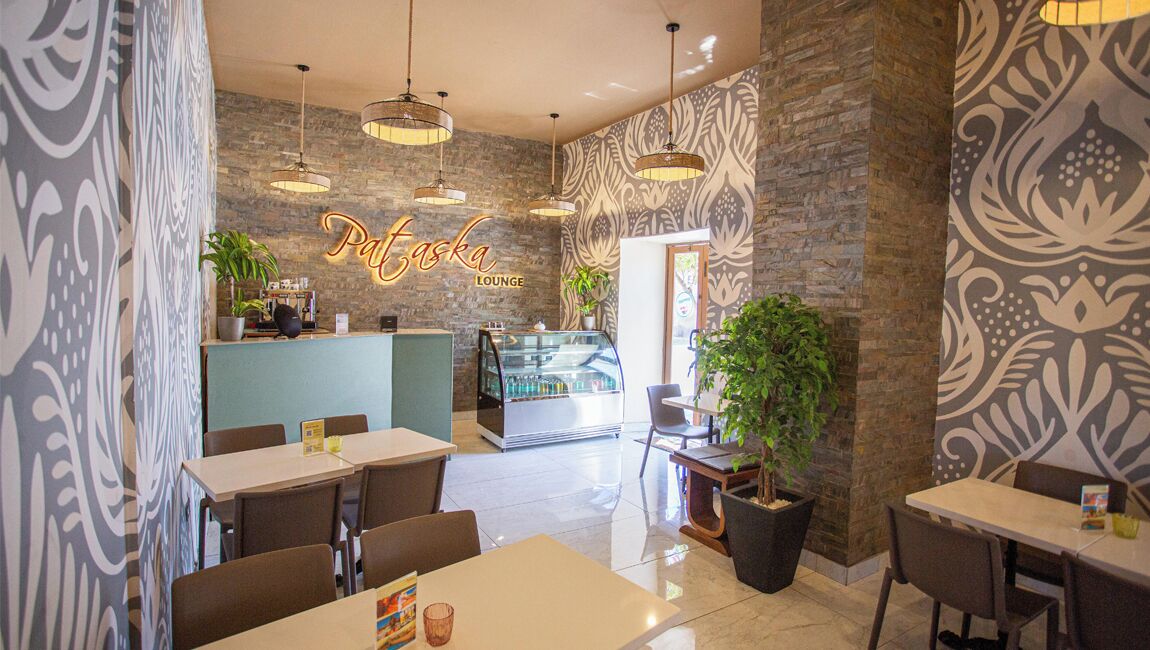 Un salon moderne avec un mur en pierre, un bar à café et plusieurs tables et chaises.