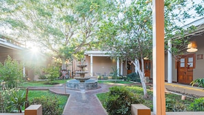 A courtyard with a central fountain, surrounded by greenery and a building with a wooden door. - Terral Hotel & Spa (Vicuña)