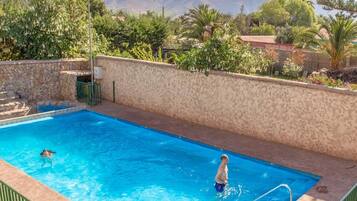 Una piscina al aire libre, sillones reclinables de piscina