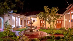 A courtyard with a fountain, potted plants, and a building with a wooden door and windows. - Terral Hotel & Spa (Vicuña)