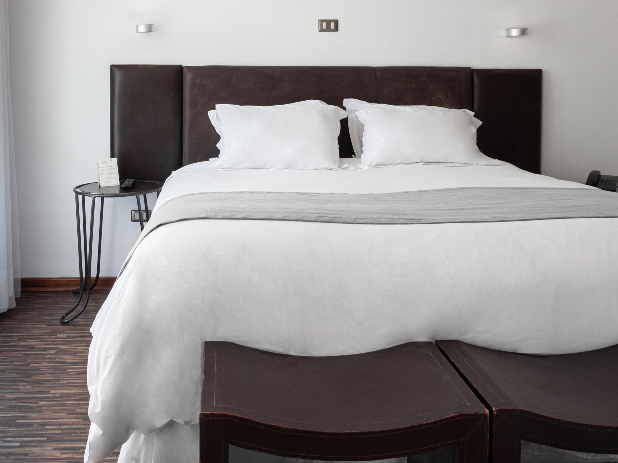 A hotel room with a large bed, two bedside tables, and a small desk with a chair.