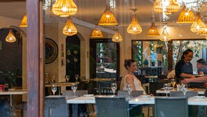 A restaurant interior with multiple dining tables and chairs, warm lighting, and a large window with a view of the outdoors. - Terral Hotel & Spa (Vicuña)