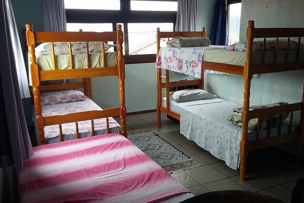 A room with two bunk beds, a single bed, and a patterned rug.