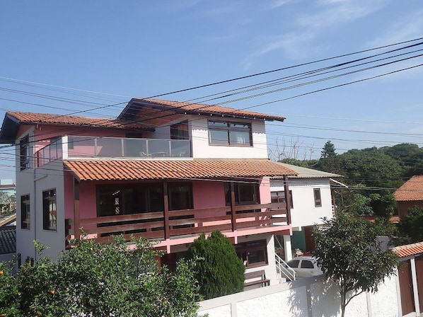 A multi-story building with a balcony, surrounded by trees and power lines.