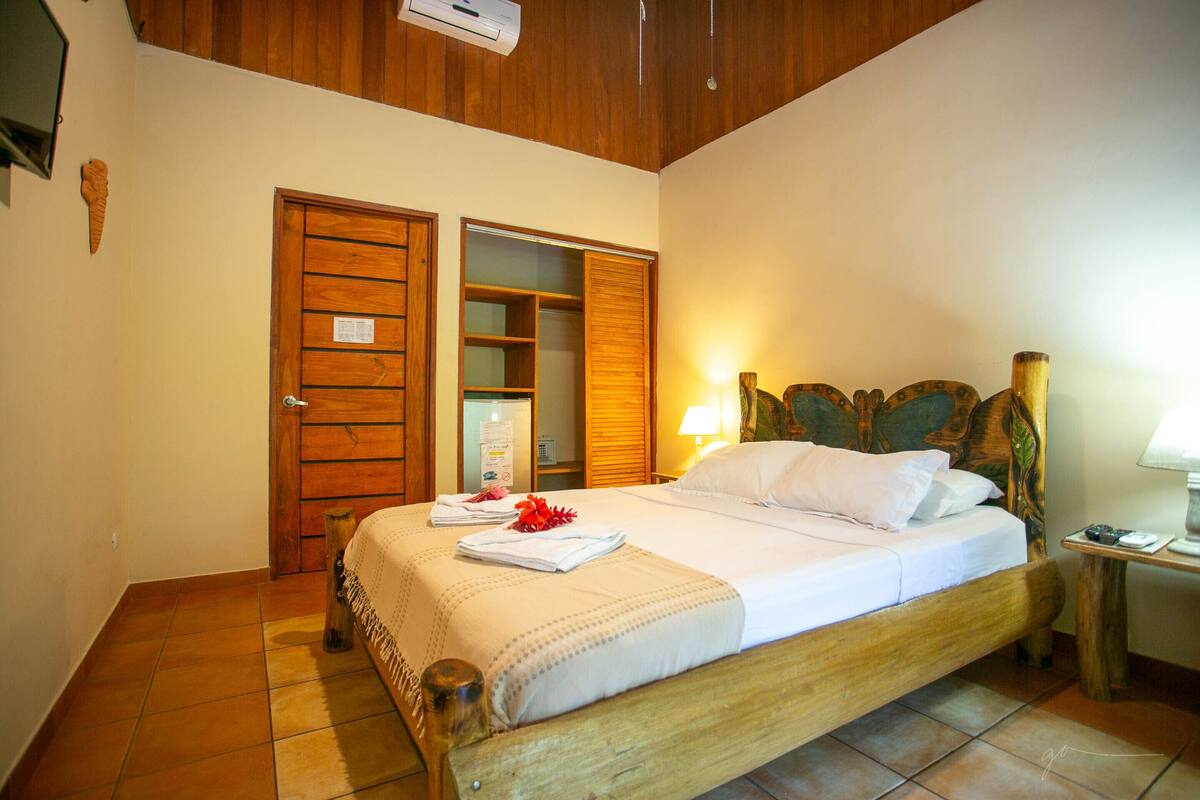A neatly made bed with a wooden headboard, a bedside table with a lamp, and a wooden wardrobe with a mirror.