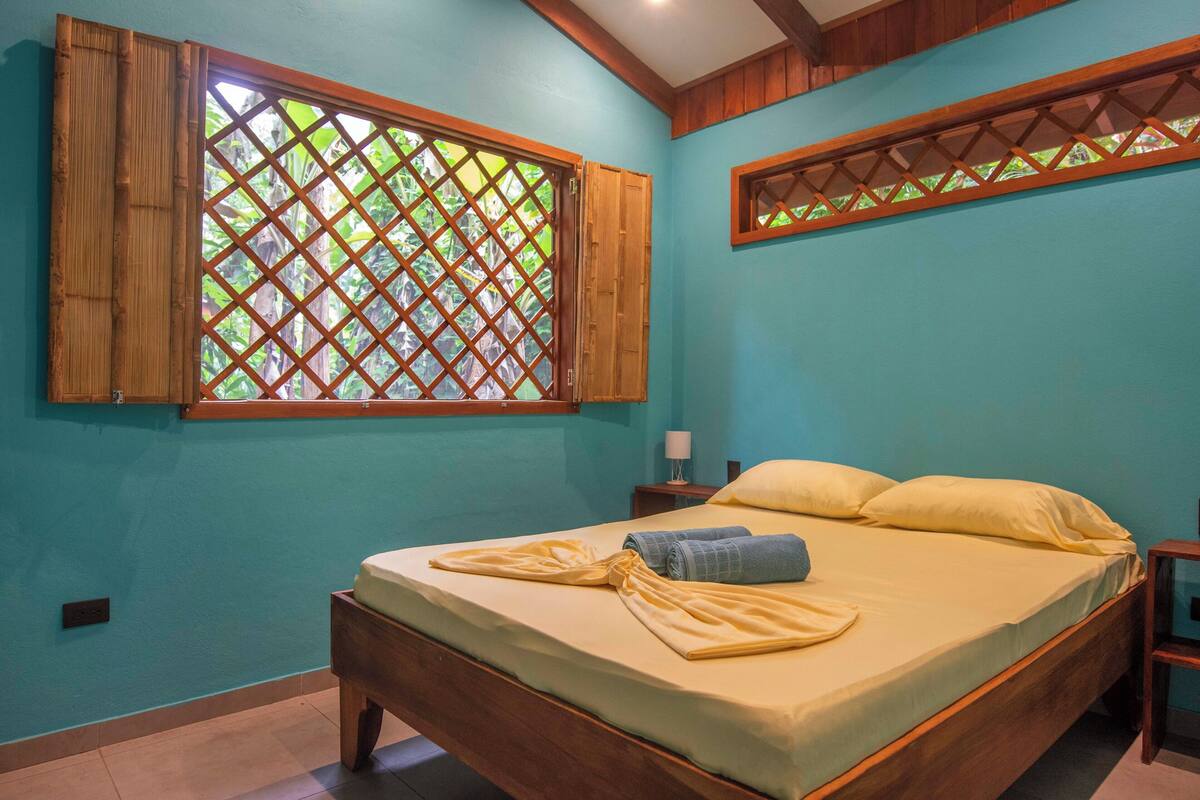 A bedroom with a bed, wooden headboard, and a window with a lattice design.