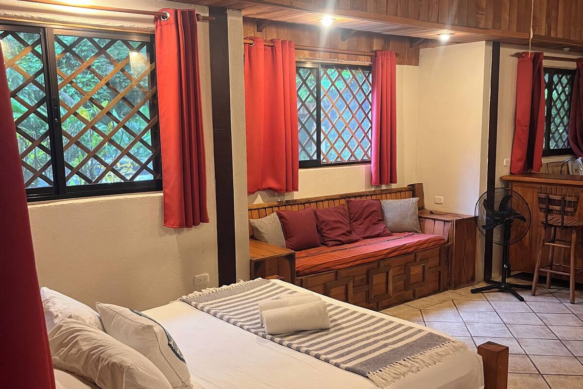 A wooden-framed room with a bed, a bench, and a small table.