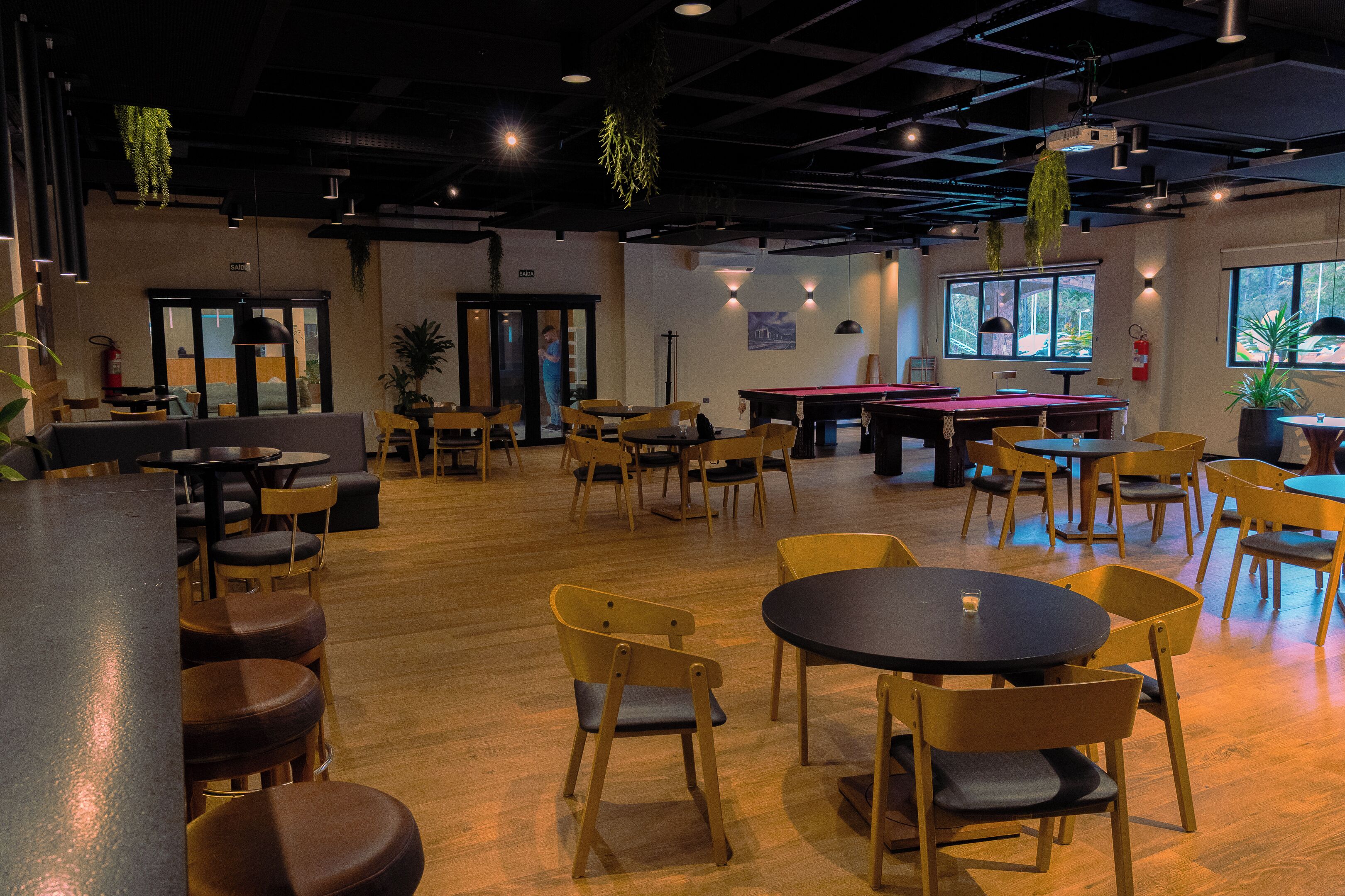 Un espacio interior amplio con diversas opciones de asientos, incluyendo mesas redondas y sillas, una mesa de billar y una zona de bar.