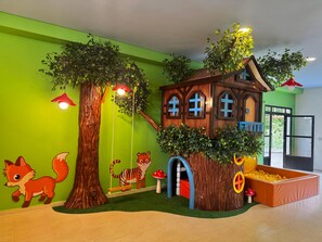 Un espace de jeux pour enfants avec une cabane dans les arbres, des balançoires et une piscine à balles.