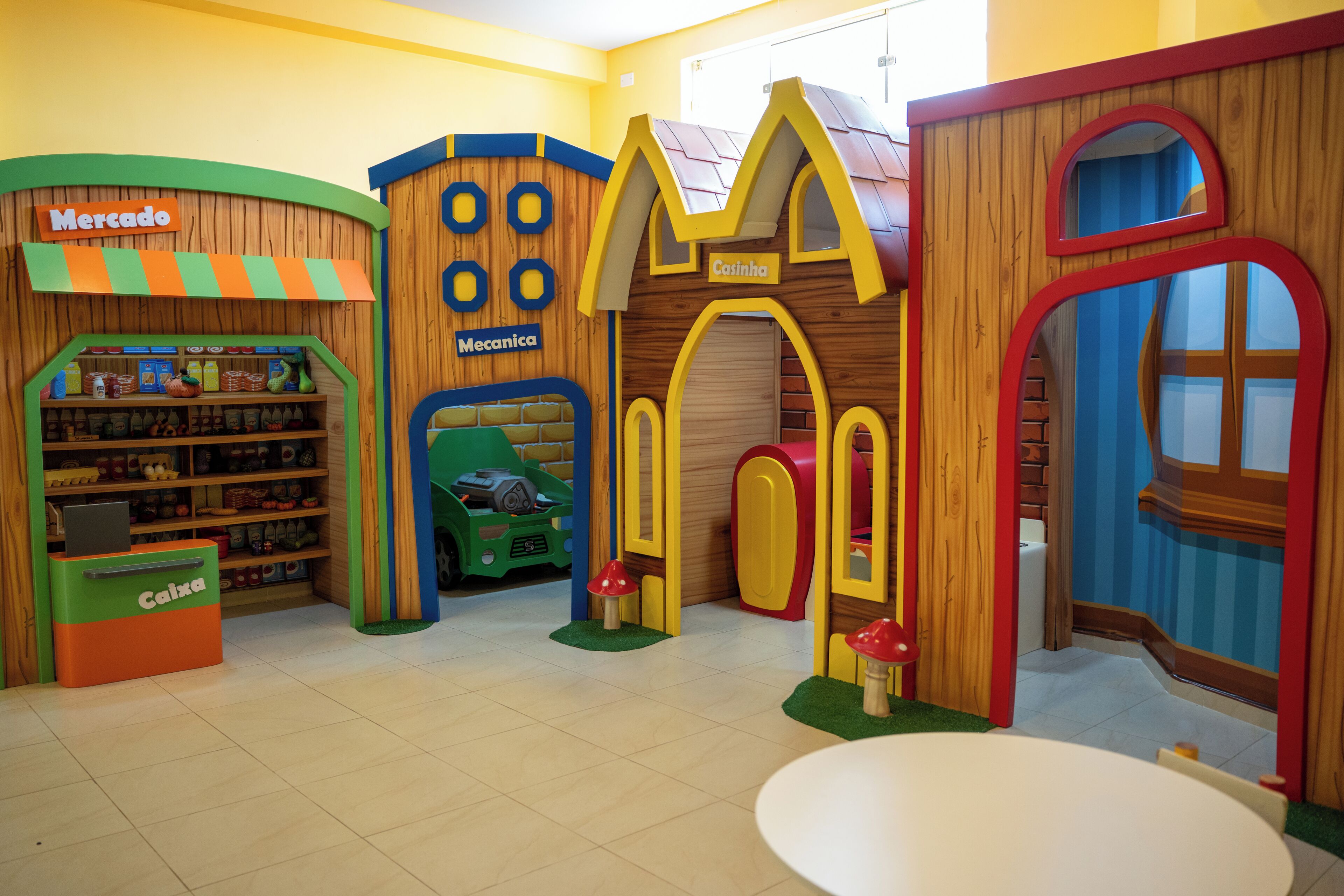 A children's play area with a toy store, a green toy car, and a red mushroom.
