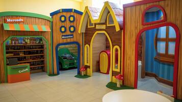 A children's play area with a toy store, a green toy car, and a red mushroom.