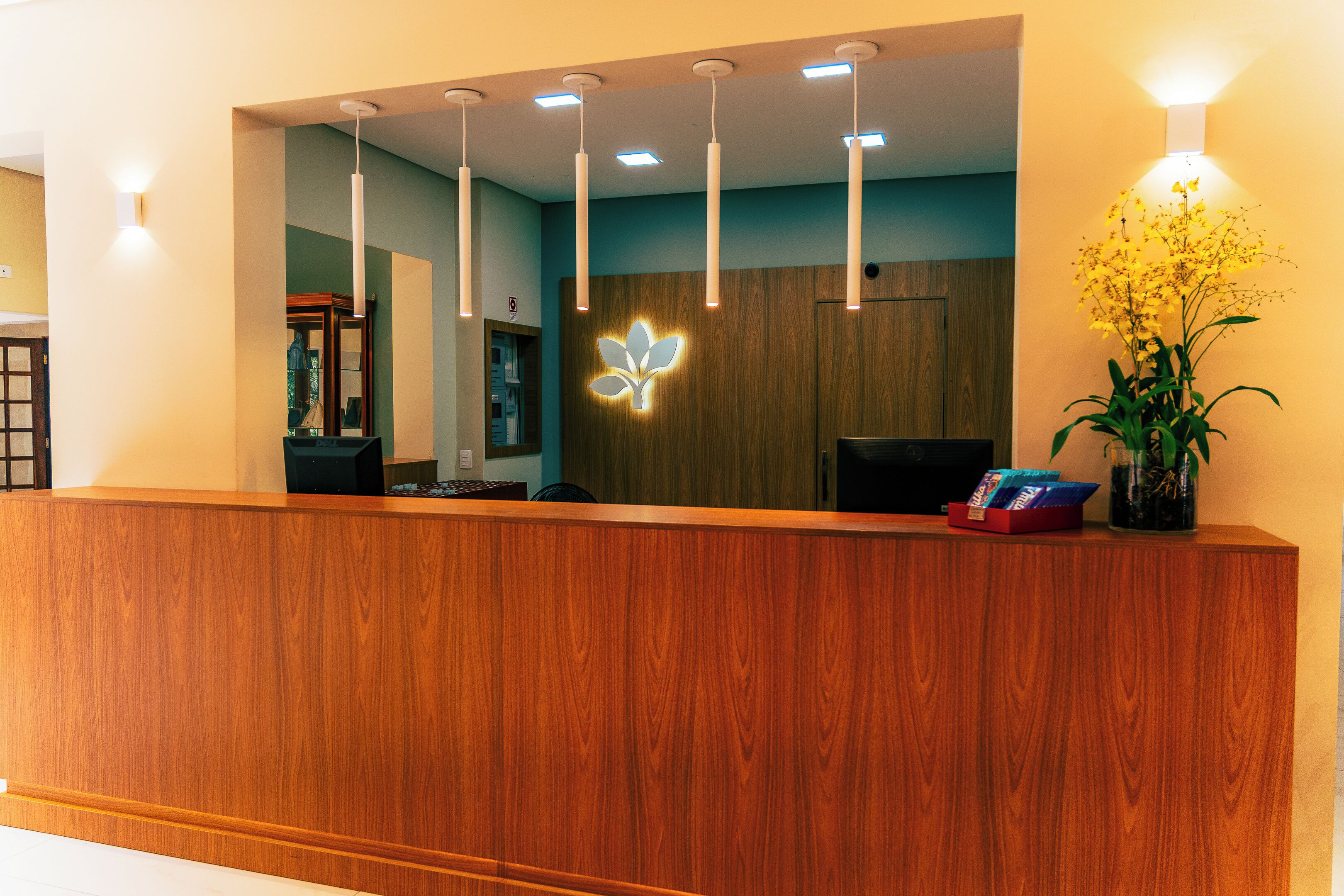 A wooden reception desk with a floral light fixture above it.