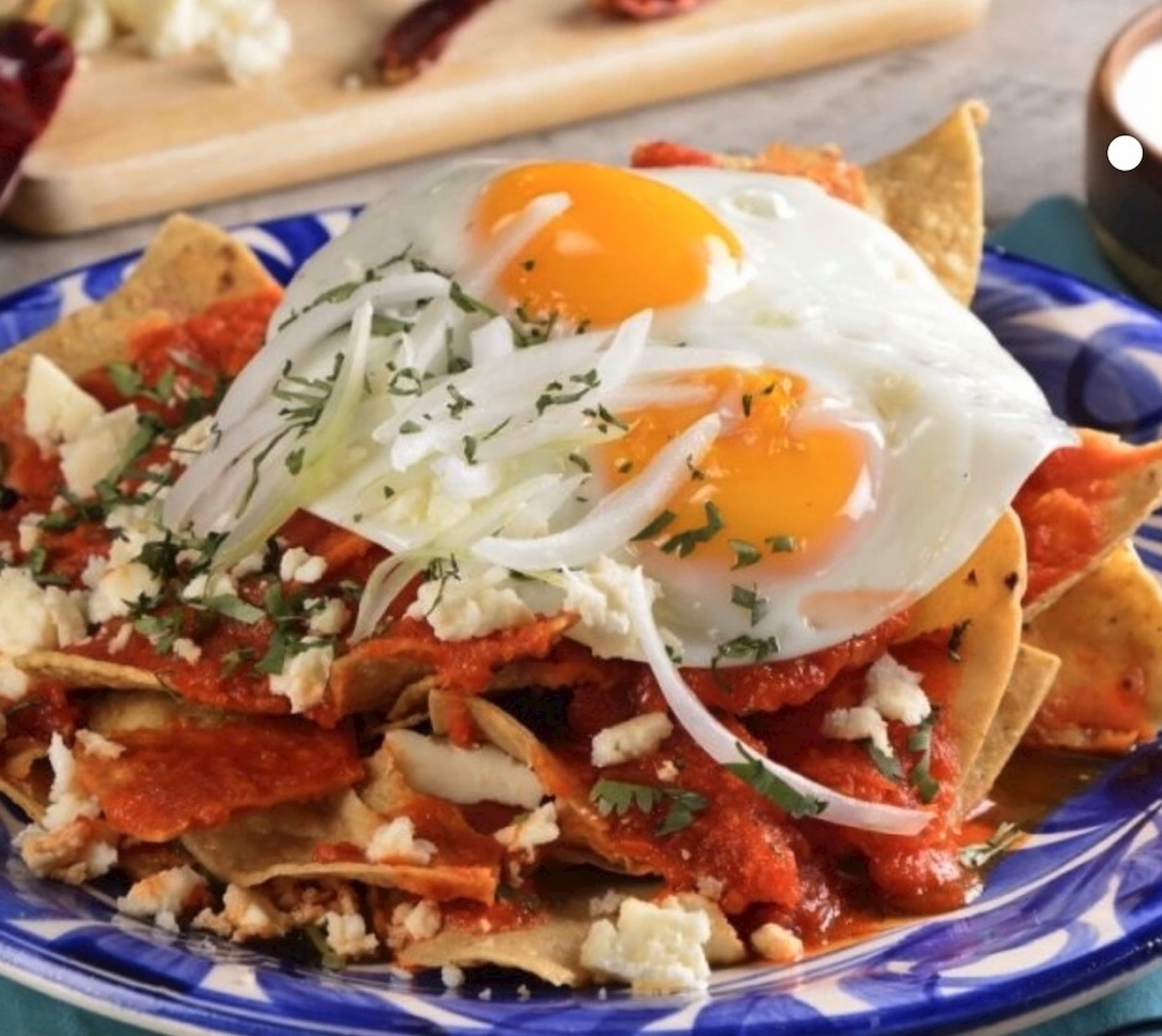 En tallrik med nachochips, täckt med ost, jalapeños och ett stekt ägg.
