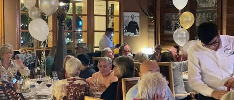 Un restaurant au décor intérieur en bois, avec des tables recouvertes de nappes blanches et décorées de ballons.