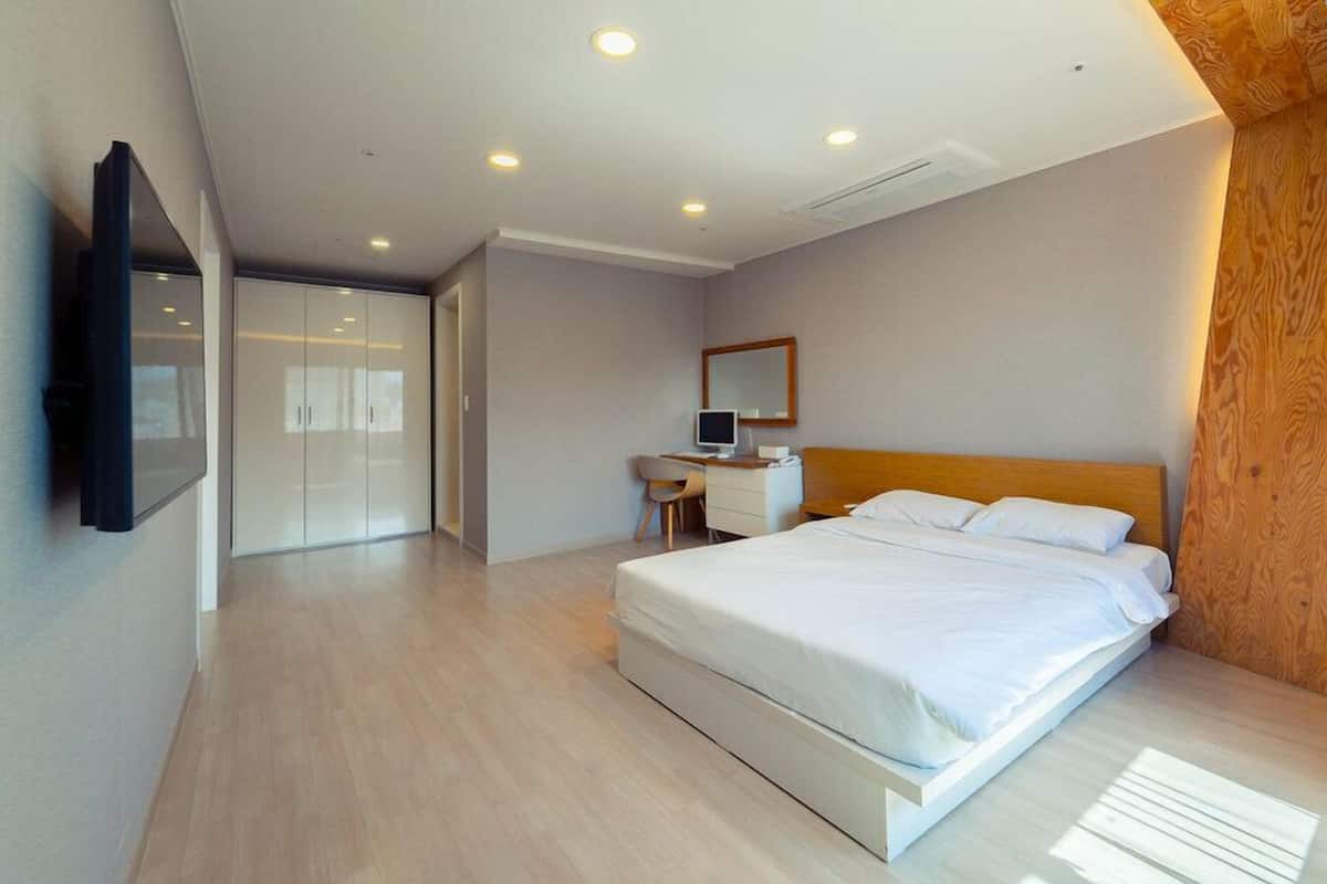 Un dormitorio moderno con una cama grande, un escritorio y un televisor montado en la pared.