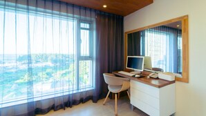 Un espace de bureau moderne comprenant un bureau, une chaise, un ordinateur et une grande fenêtre avec des rideaux.