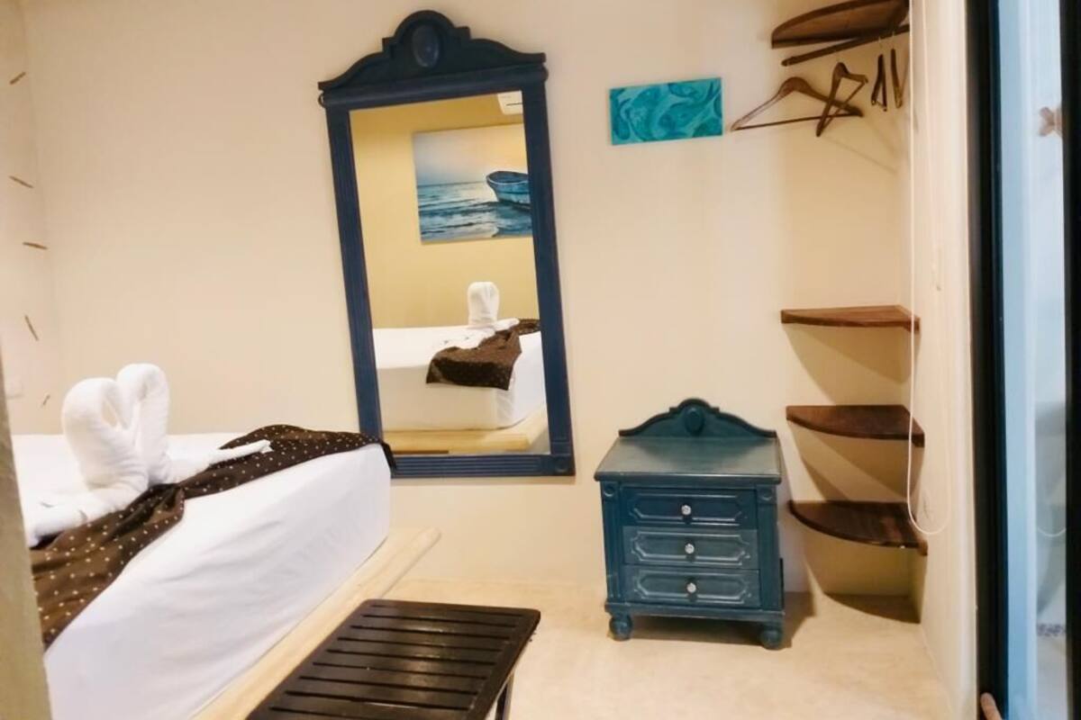 A bedroom with a bed, a dresser, a mirror, and a painting on the wall.