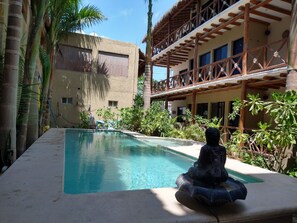 A pool with a Buddha statue, surrounded by tropical plants and a wooden balcony. - La Constanza de Rulo (Isla Holbox)