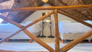 Une pièce dotée d’une structure de plafond en bois, de deux lits et de deux ventilateurs sur pied.