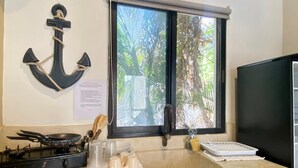Une cuisine équipée d’une cuisinière à gaz, d’un évier et d’une fenêtre donnant sur les arbres.