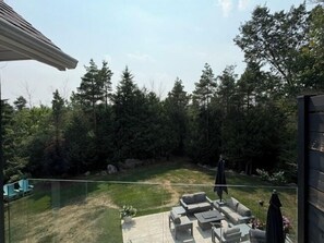 A backyard with a glass balustrade, outdoor furniture, and a lawn. - Craigleith Manor Bed & Breakfast (Collingwood)