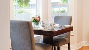 A dining table set with chairs, a vase of flowers, and a coffee mug. - Craigleith Manor Bed & Breakfast (Collingwood)