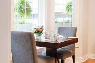 Una mesa de comedor con sillas, un florero y una taza de café.