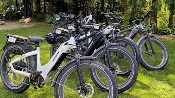 A row of stationary bicycles parked on a grassy area.