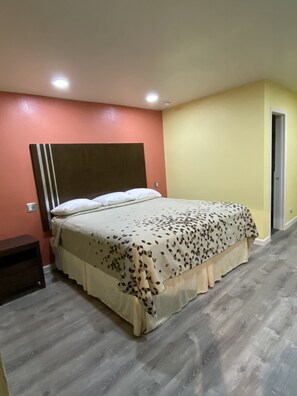 Quarto com cama, mesa de cabeceira e porta.