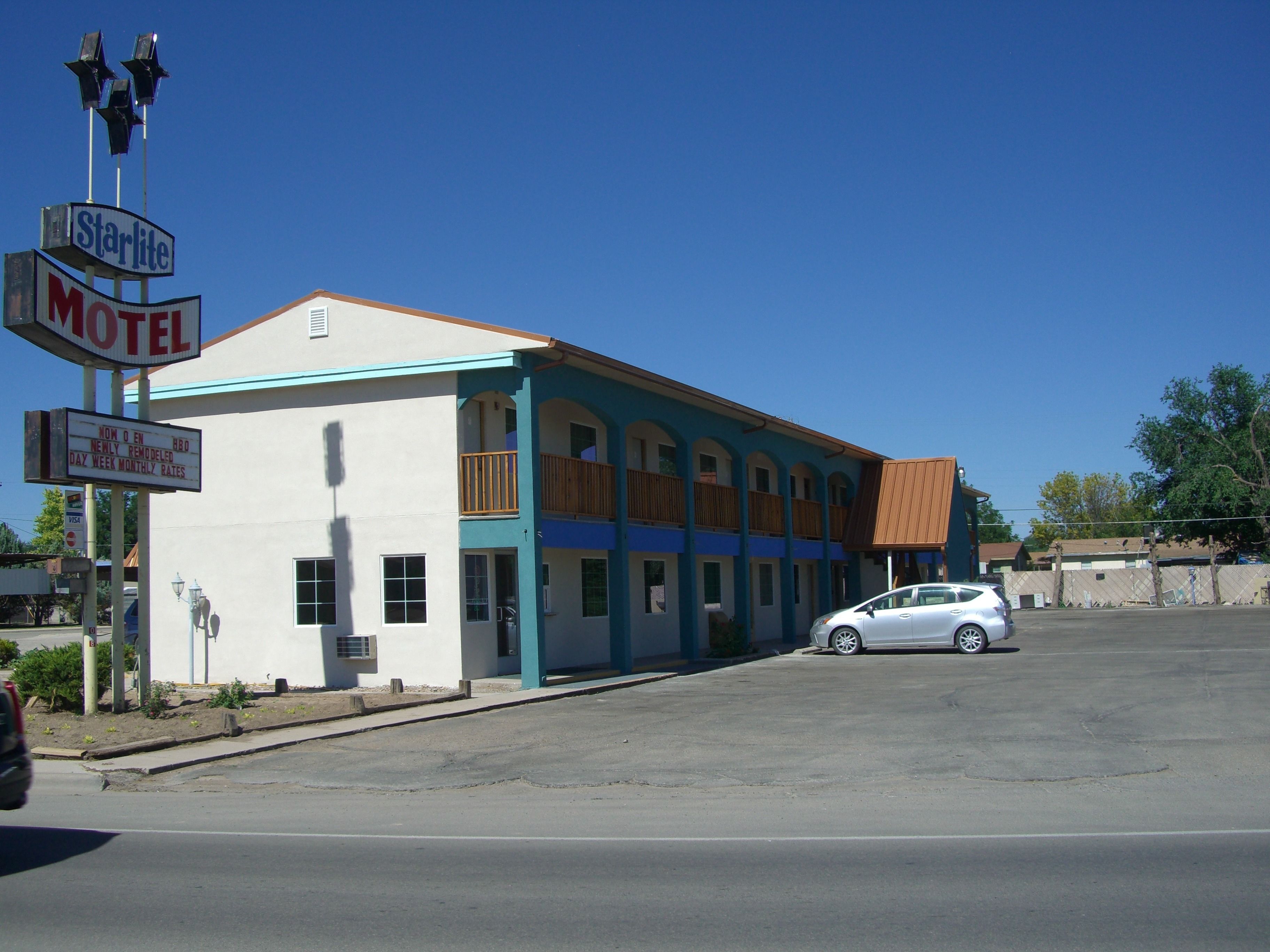 Un motel composé d’un bâtiment à deux étages, d’un parking et d’une voiture blanche garée devant.