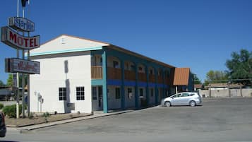 Un motel composé d’un bâtiment à deux étages, d’un parking et d’une voiture blanche garée devant.