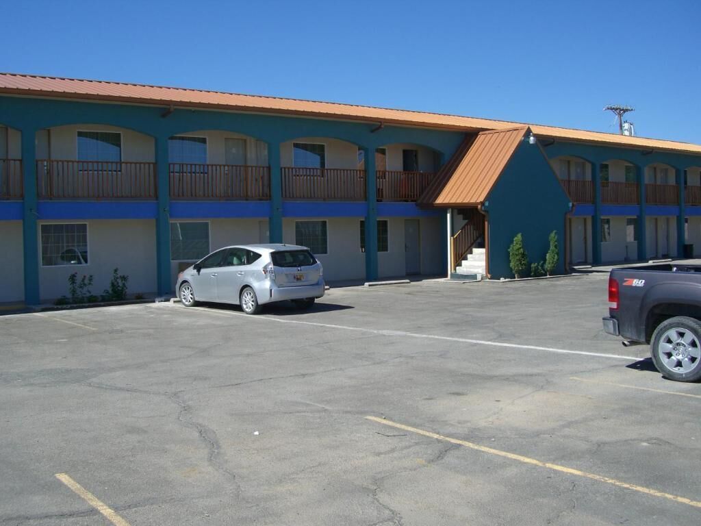 A motel with a parking lot, a silver car, and a dark-colored truck.