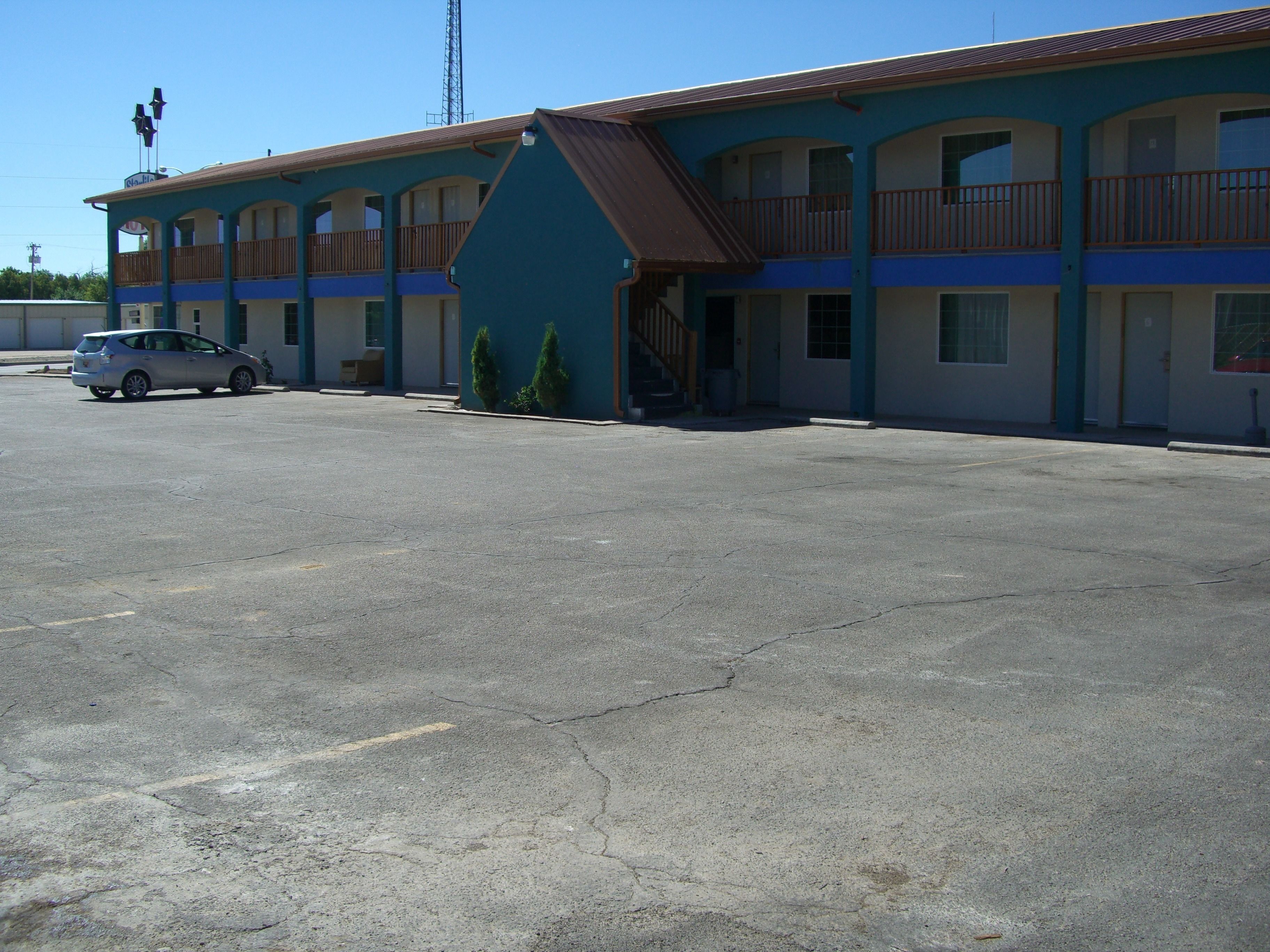 A motel with a two-story structure, a parking lot, and a car parked in front.