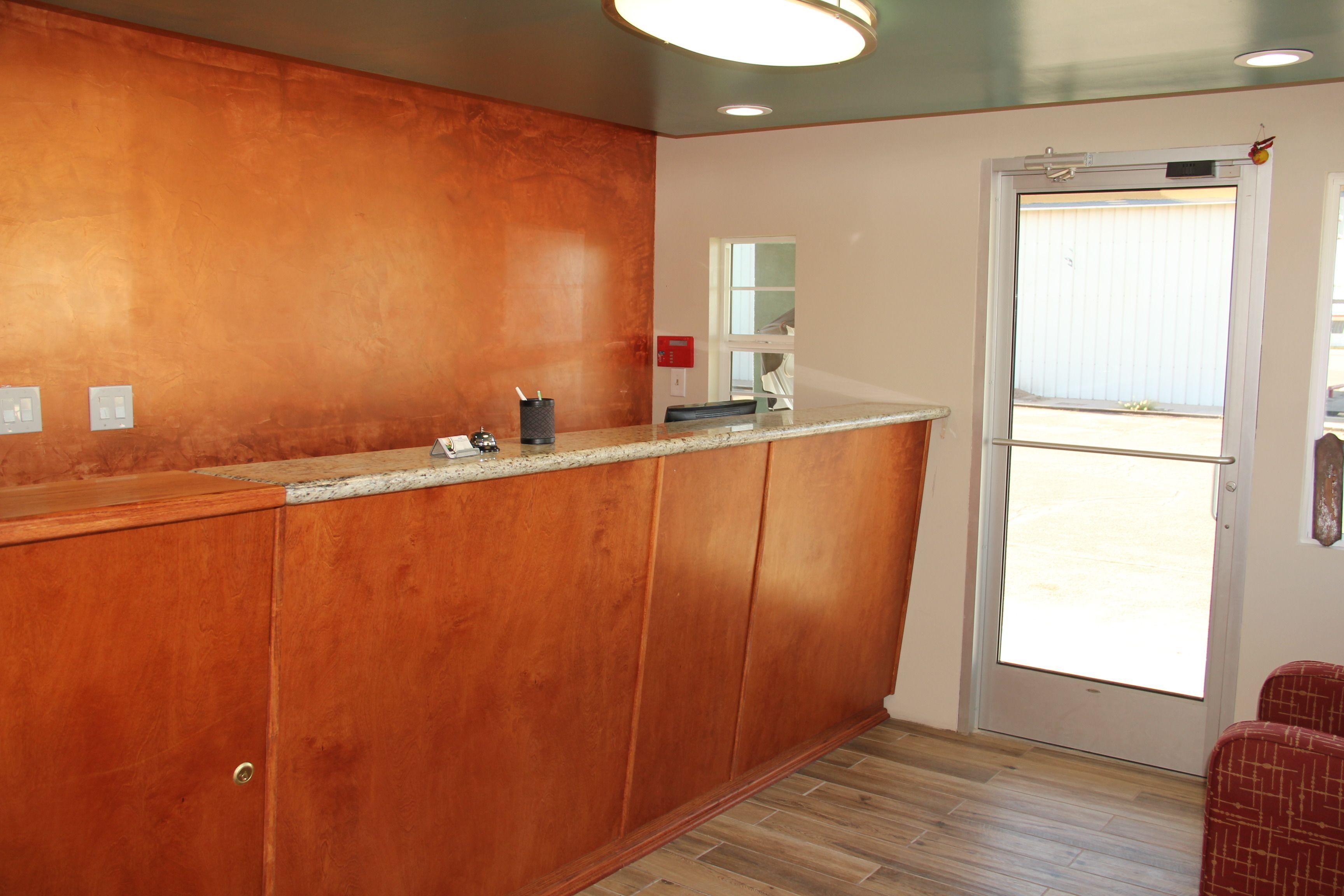 A kitchen with wooden cabinets, a granite countertop, and a door leading to a balcony.