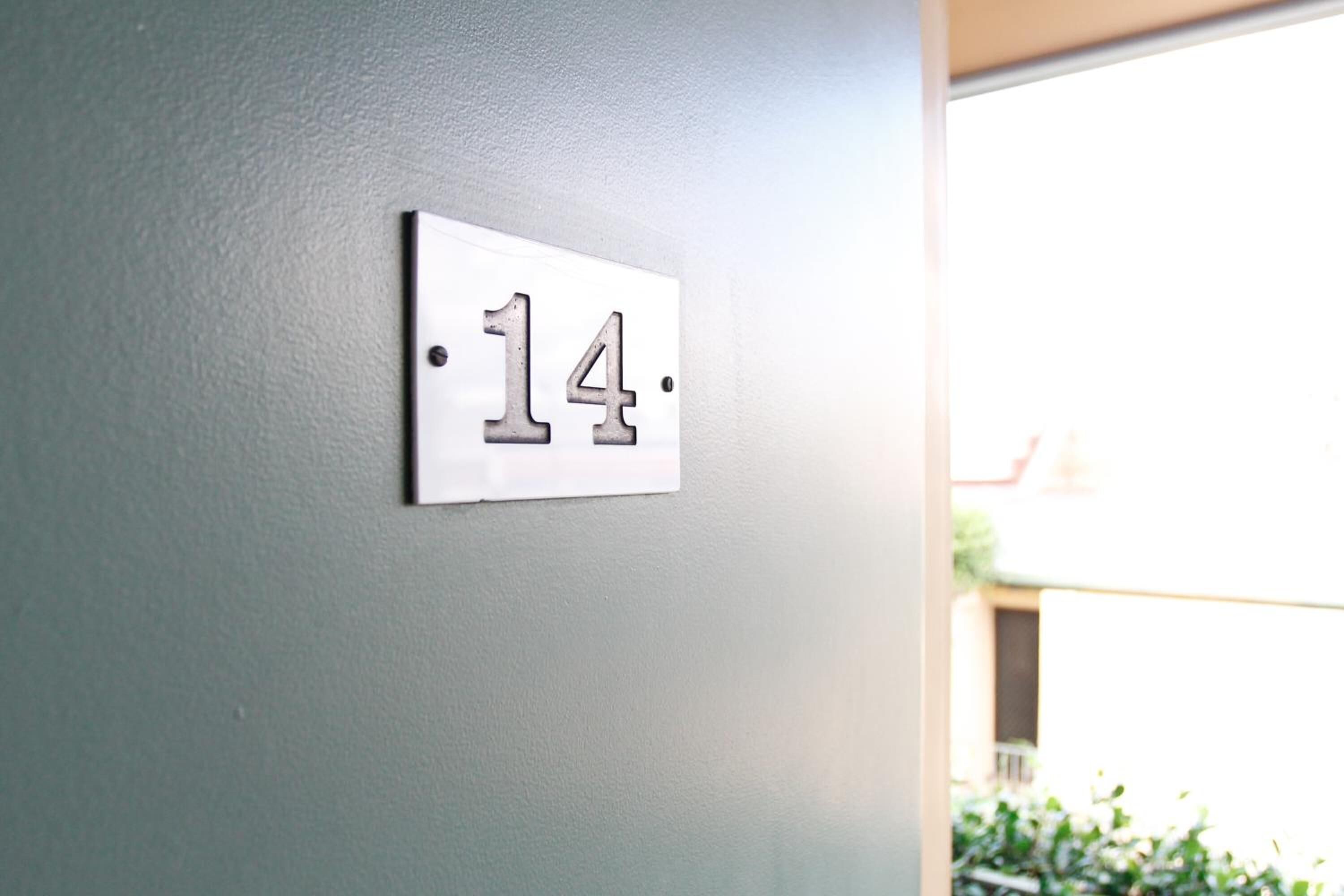 A white wall with a number plate displaying the number 14.