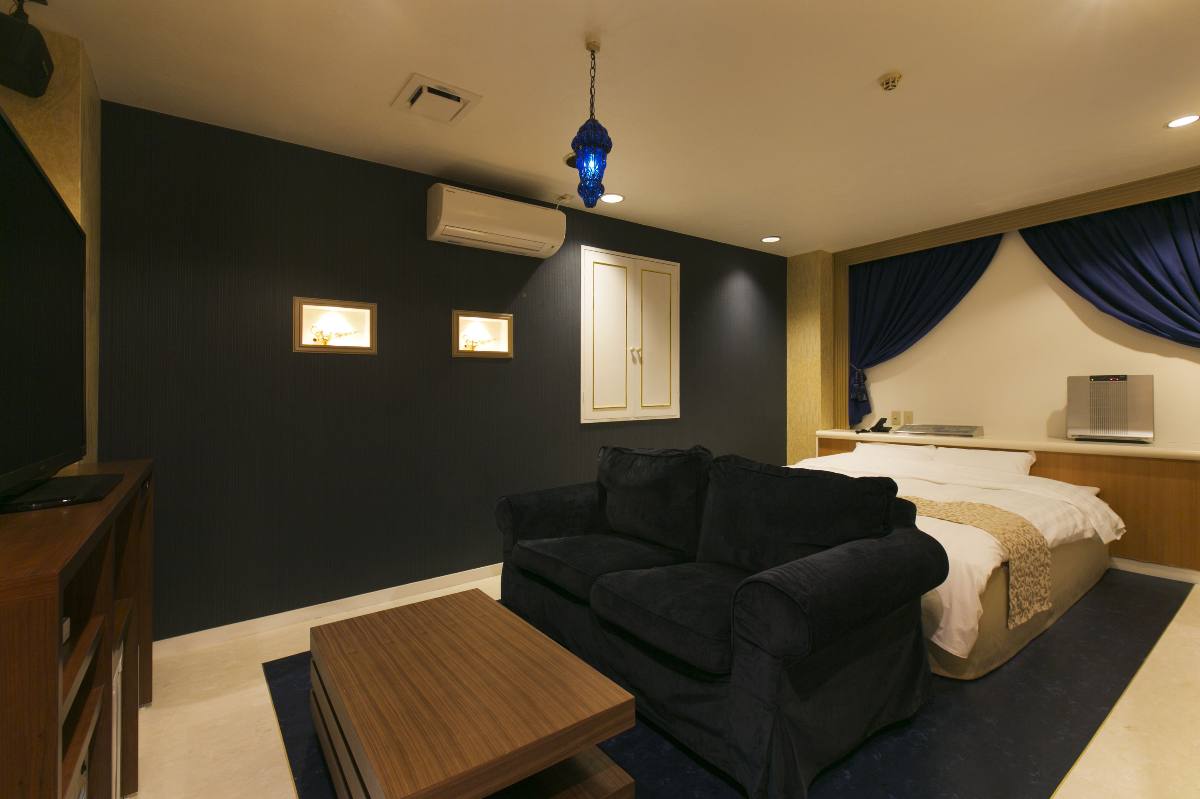 Une chambre d’hôtel avec un lit, un canapé, une petite table et un luminaire au plafond.