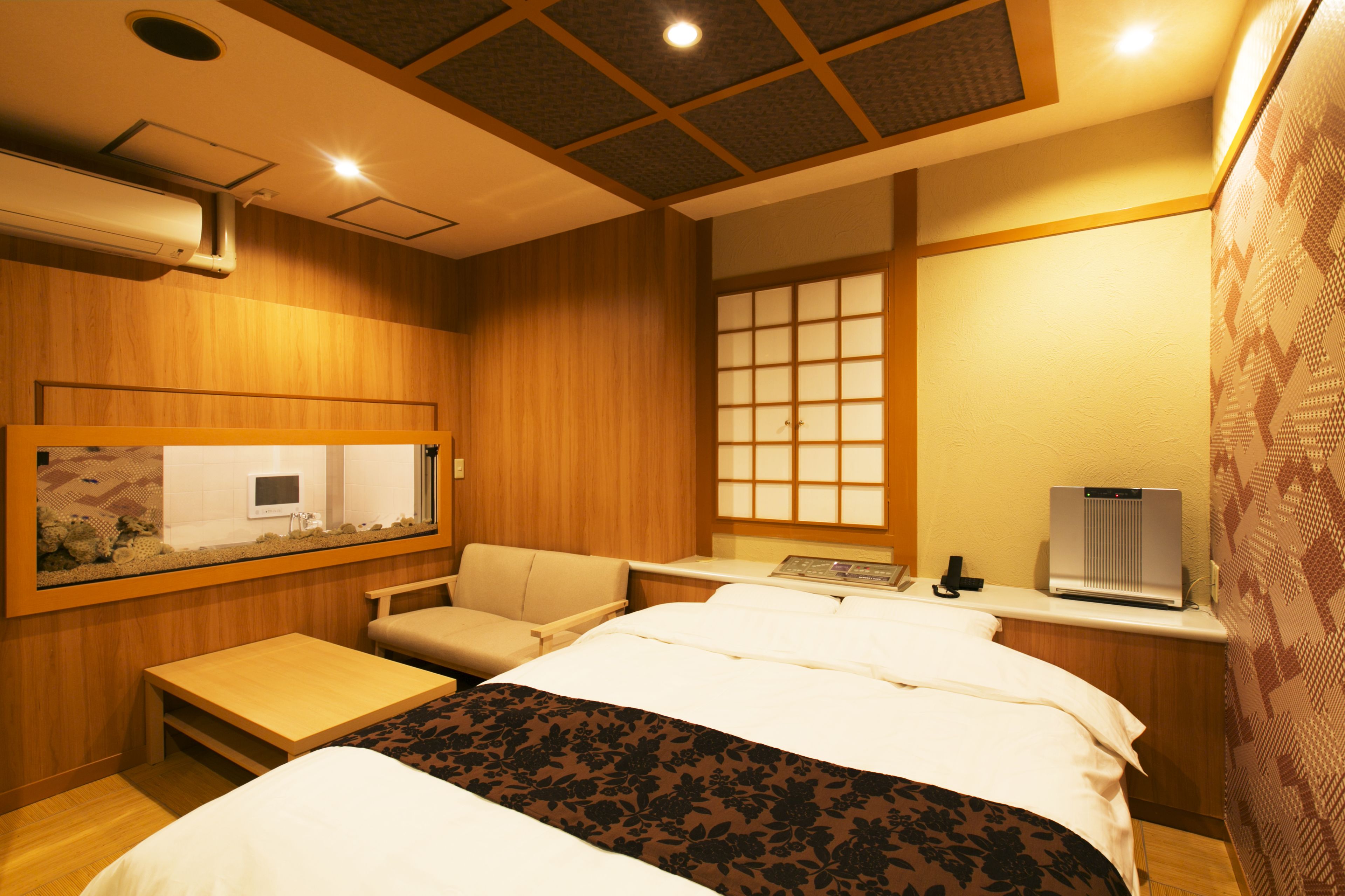 Habitación de hotel con cama, un pequeño escritorio, una silla, ventana con vistas y aire acondicionado instalado en la pared.