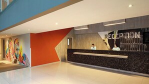 A reception area with a modern design, a reception desk, and a wall with a colorful mural. - Primera Hotel Seminyak (Seminyak)